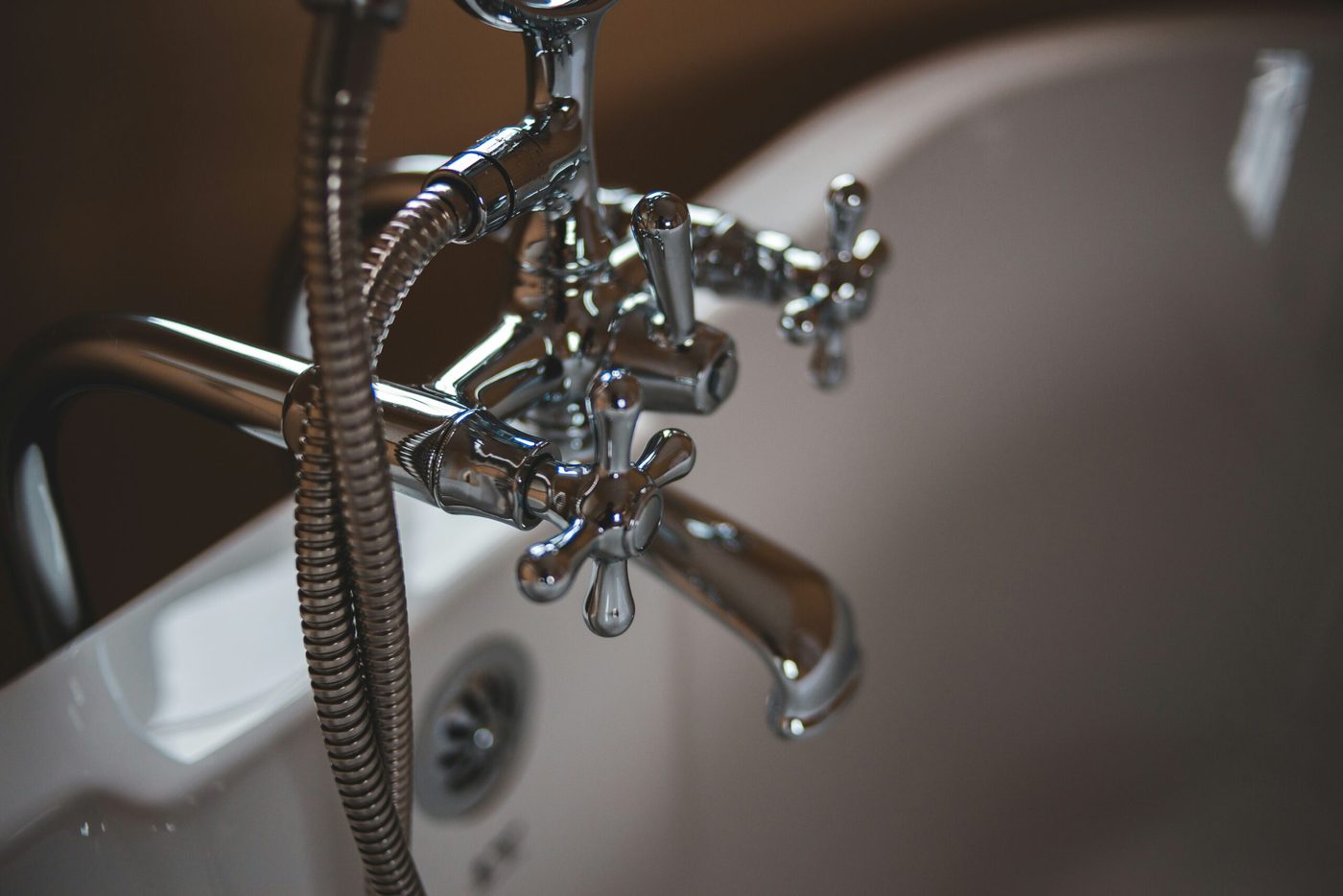 Chrome bath taps and shower hose in a well kept bathroom