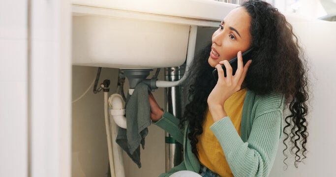 Homeowner calling for help beside a leaking kitchen sink